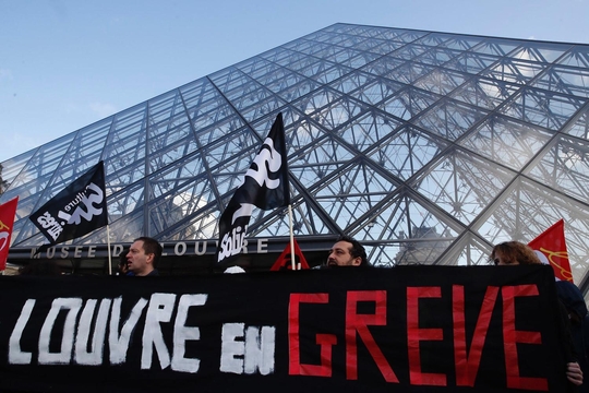 Workers holding a banner saying "Louvre en greve" outside of the Louvre in Paris. Workers holding a banner saying "Louvre en greve" outside of the Louvre in Paris.