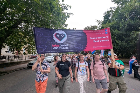Photo of gameworkers carrying a purple and pink IWGB Games Workers union banner on a protest. Photo of gameworkers carrying a purple and pink IWGB Games Workers union banner on a protest.