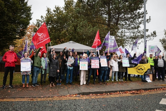 Manchester workers rally for increased funding in mental health services, holding trade union signs and flags in support of their cause.