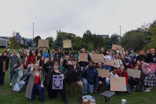 A picket line demonstration of postgraduate workers on the grass in front of their university